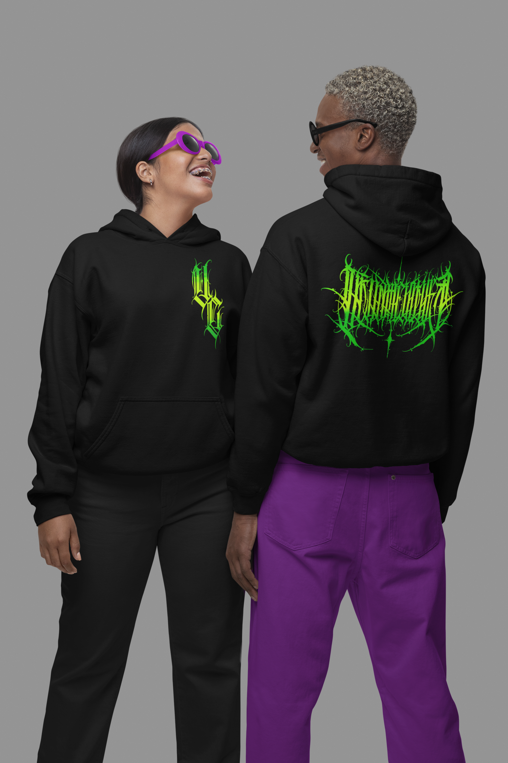 man and woman looking at each other laughing and wearing black hoodies featuring green venom culture logo on front and poison culture design on back